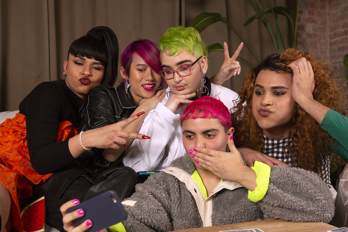 Five people of that vary on the gender spectrum posing for a group selfie photo.