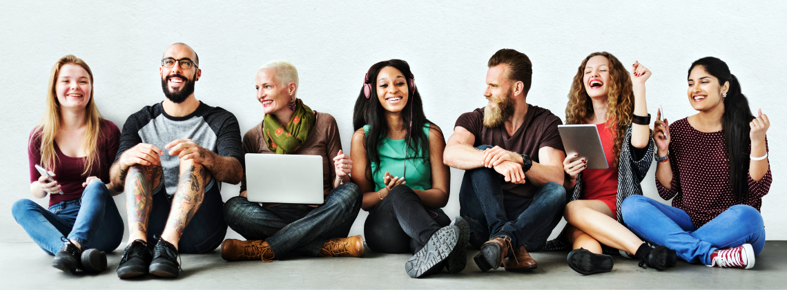 Large photo of a 7 people of diverse ethnicities, each with various technology: smartphone, laptop, headphones, tablet... (Photo by Kelly Sikkema on Unsplash)