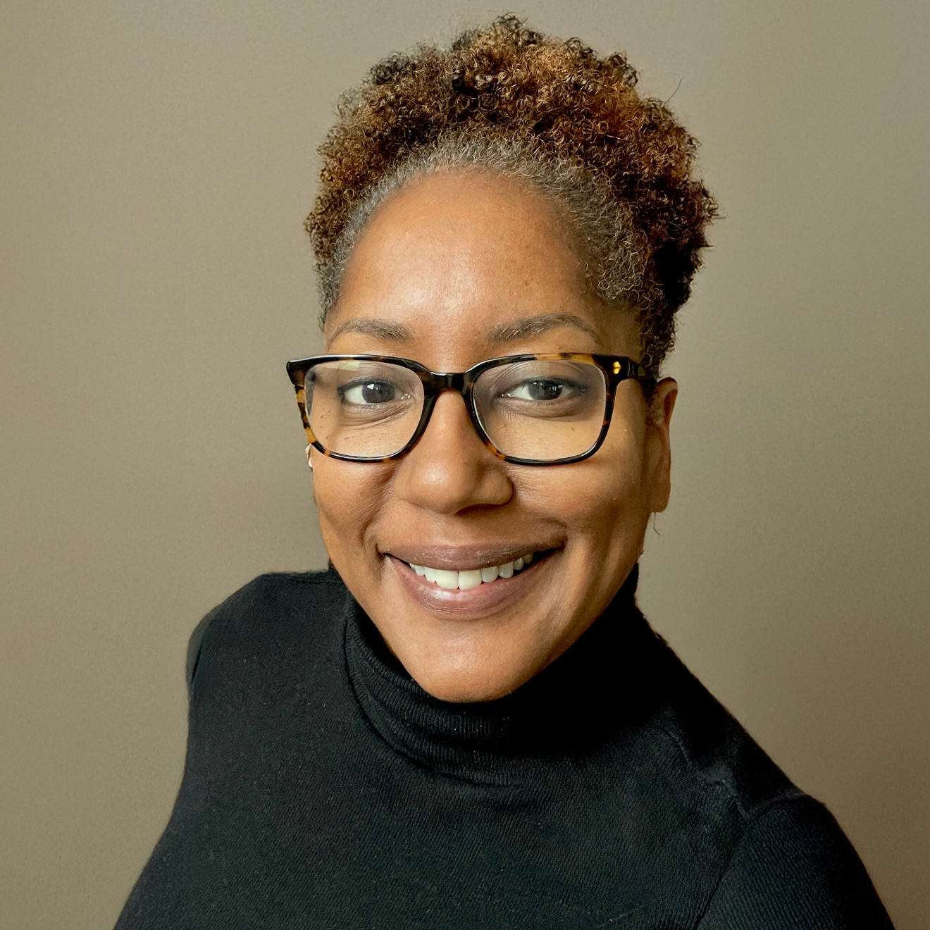 headshot of Trina with short curly Afro, glasses and a warm smile.